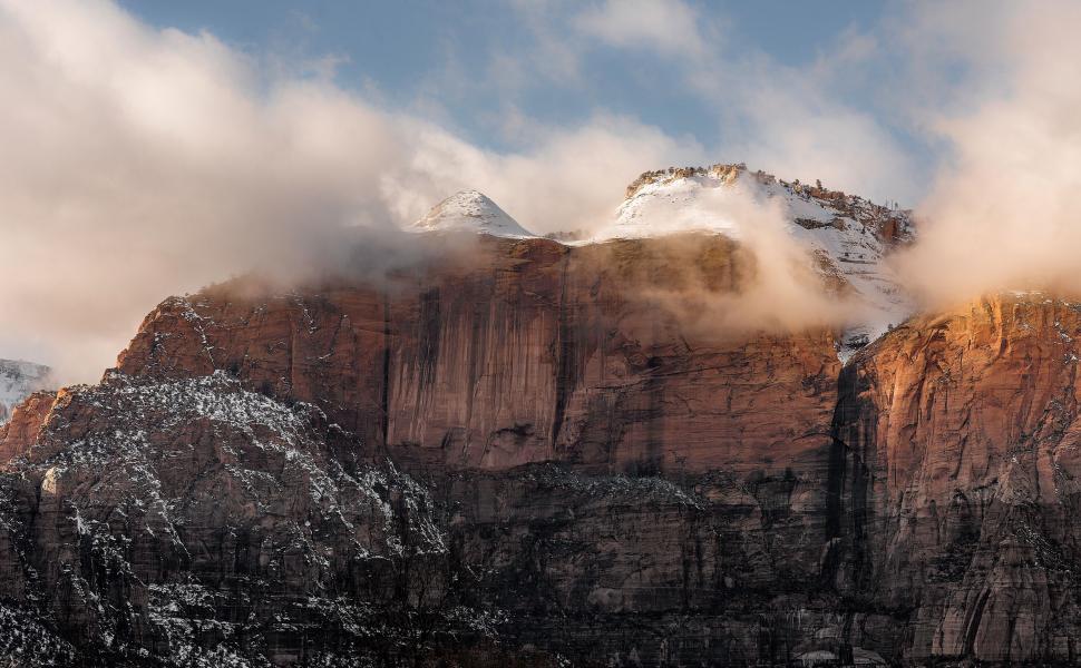 Free Image of Mountain Covered in Snow and Clouds Under Blue Sky 