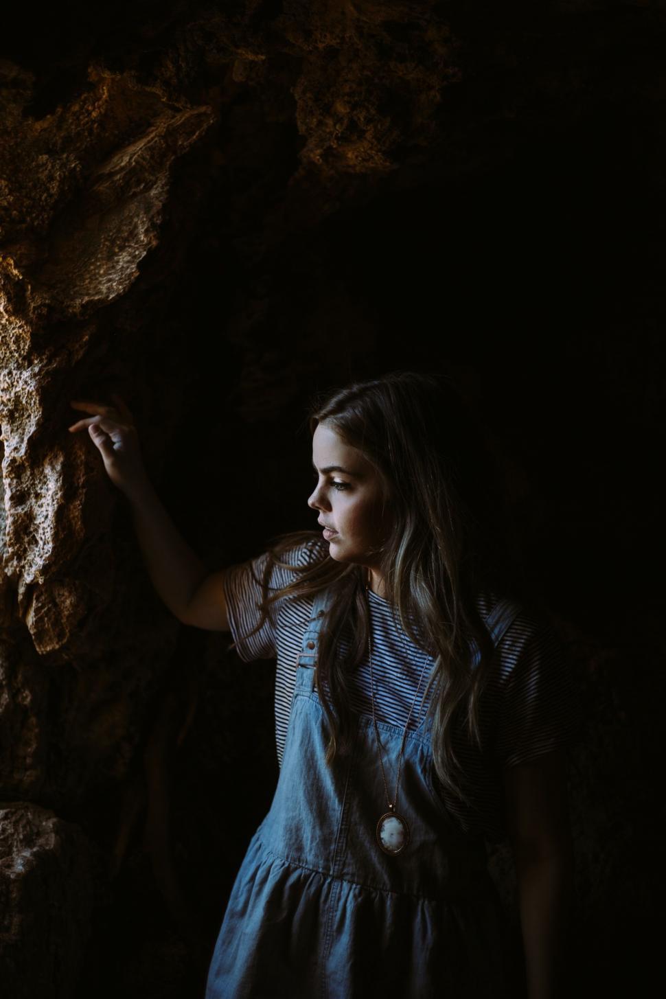 Free Image of Girl in Blue Dress Standing Next to Rock 