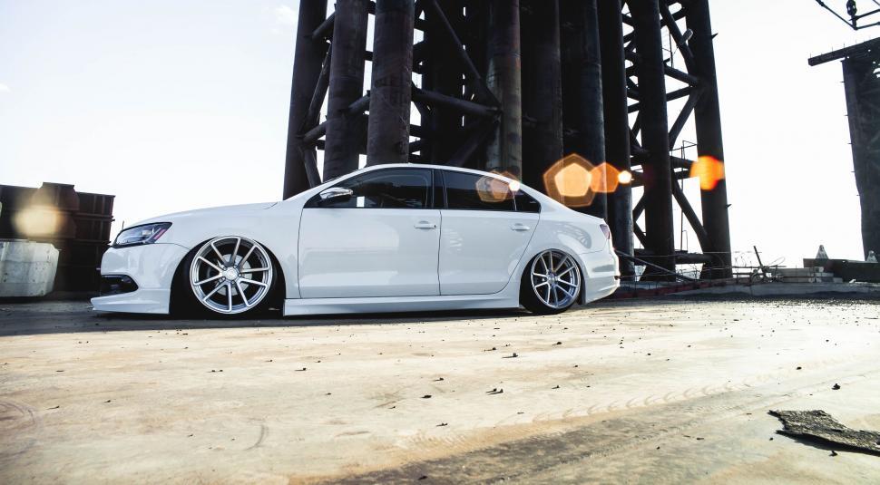 Free Image of White Car Parked in Front of Tall Structure 
