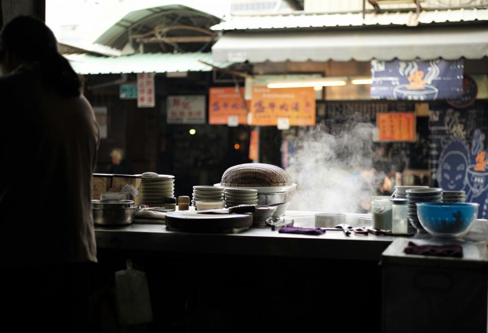 Free Image of Woman Standing in Front of Filled Kitchen With Pots and Pans 