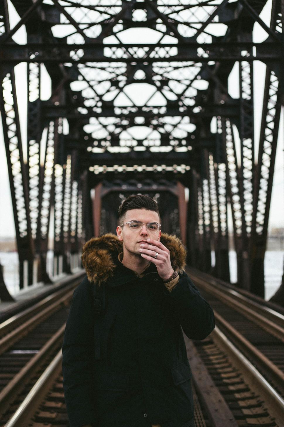 Free Image of Man Standing on Train Track Smoking a Cigarette 