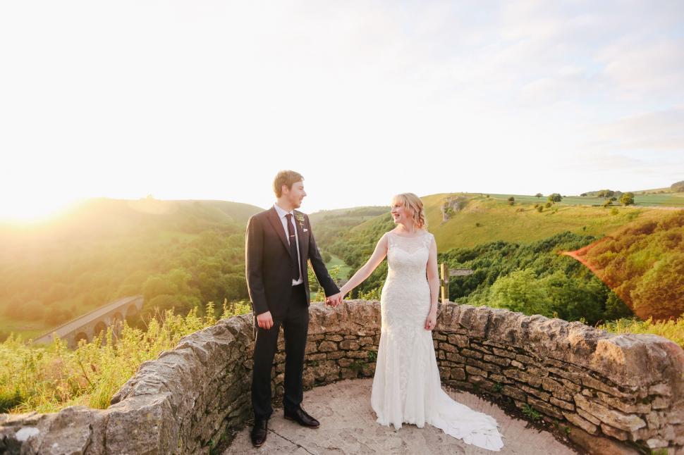 Free Image of Bride and Groom Standing on Stone Wall 