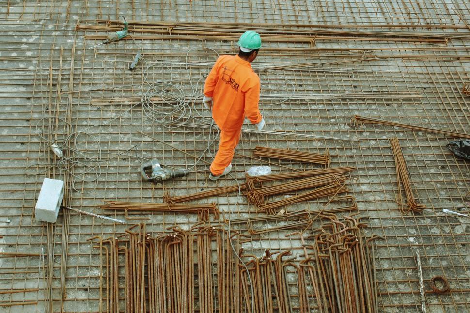 Free Image of Man in Orange Jumpsuit Standing on Construction Site 