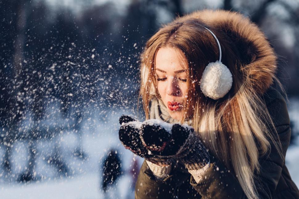 Free Image of Woman Wearing Headphones Blowing Snow 