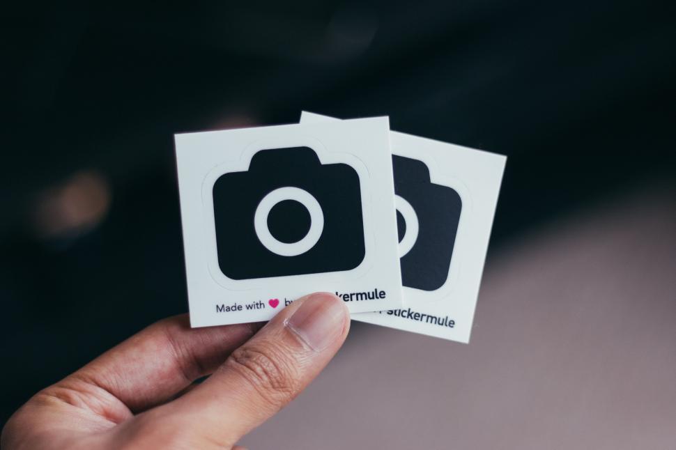 Free Image of Person Holding Up Two Camera Stickers 