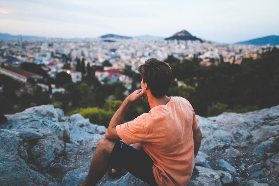 Free Image of Man Sitting on Top of Rock Covered Hillside 