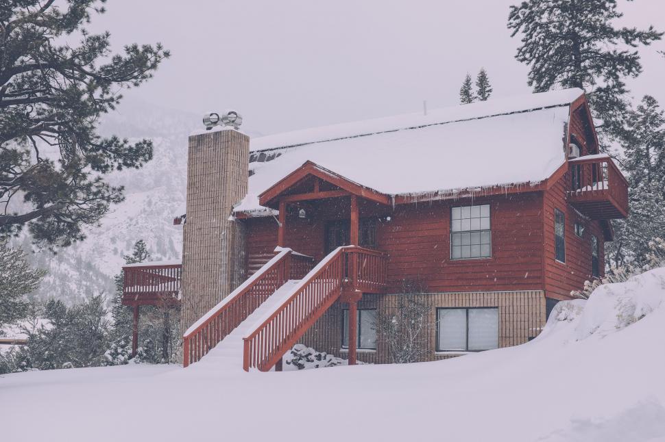 Free Image of Red House Covered in Snow Next to Trees 