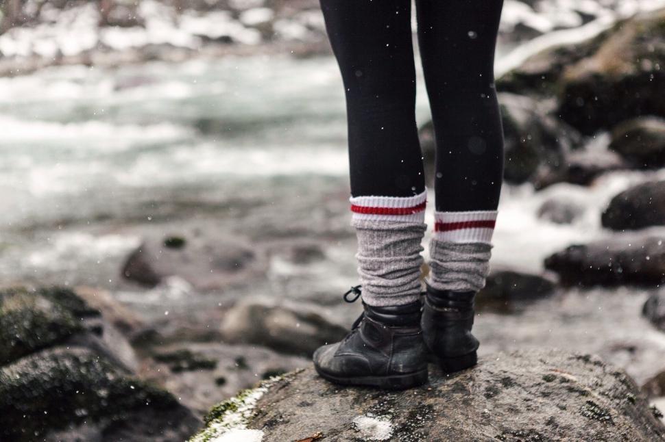 Free Image of Person Standing on Top of Rock Next to River 