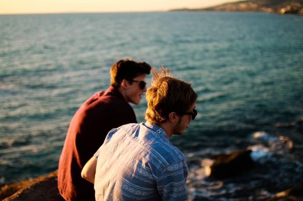 Free Image of Two People Sitting on a Rock 