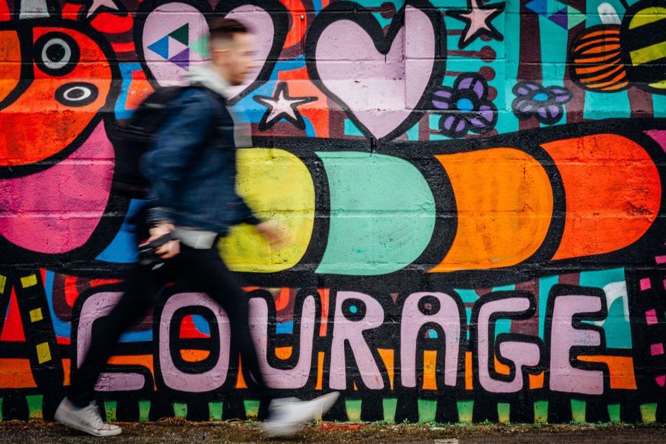 Free Image of Man Walking Past Wall With Mural 