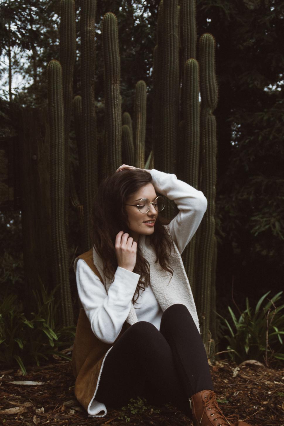 Free Image of Woman Sitting in Front of Cactus 