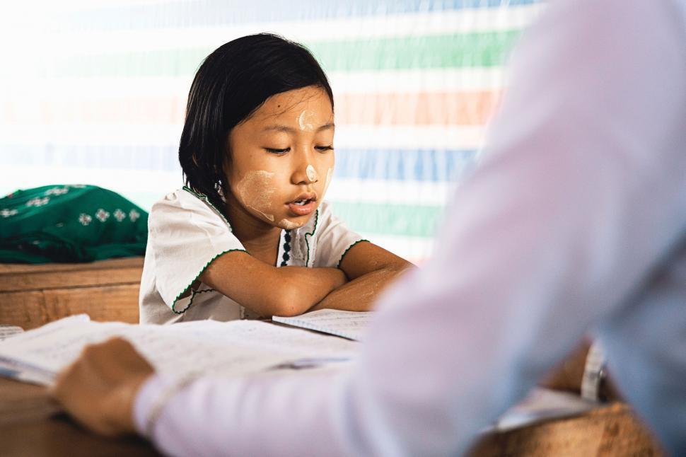 Free Image of Young Girl Sitting at Desk With Folded Hands 
