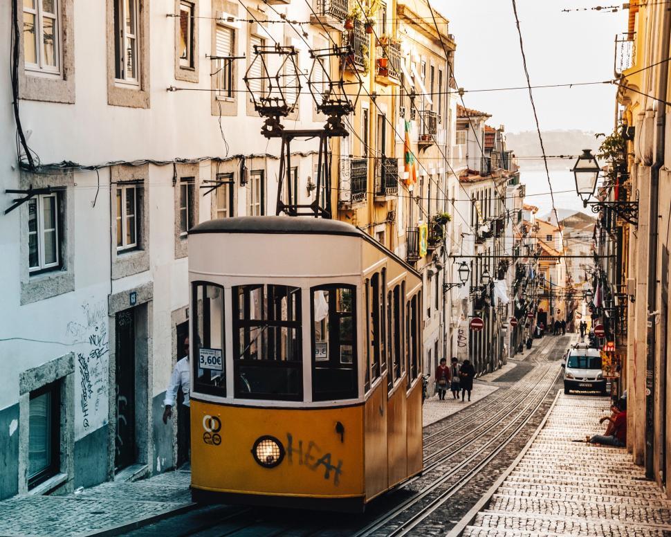 Free Image of Yellow Trolley Car Traveling Down Street by Tall Buildings 