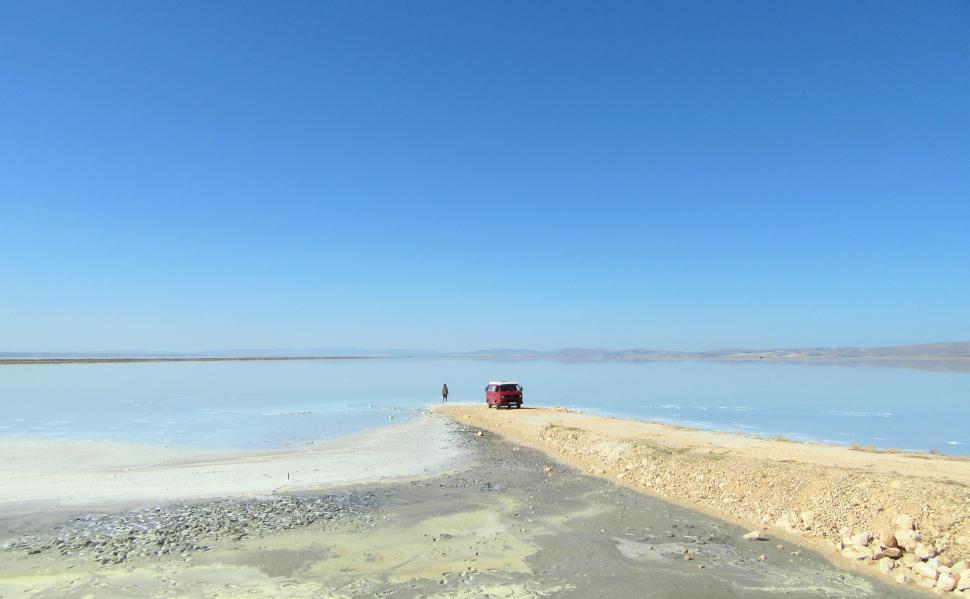 Free Image of Truck Driving Along Road Beside Body of Water 