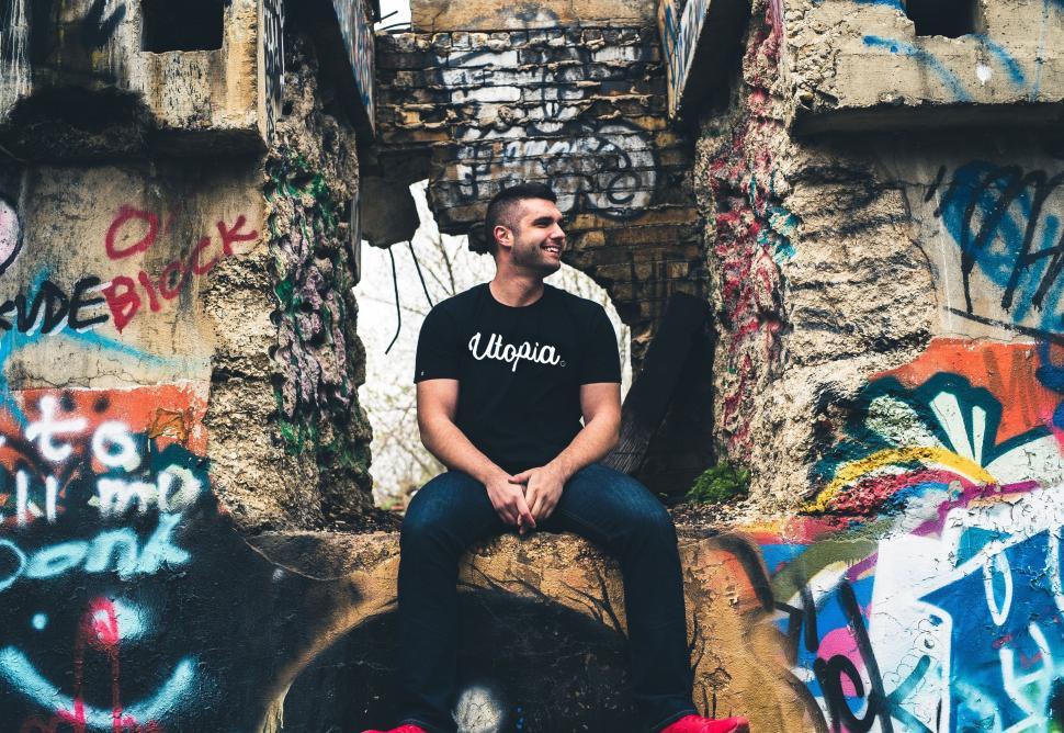 Free Image of Man Sitting on Graffiti-Covered Wall 
