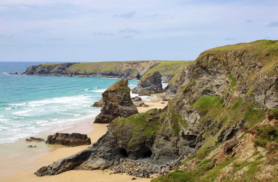 Free Image of Sandy Beach Next to Rocky Cliff 