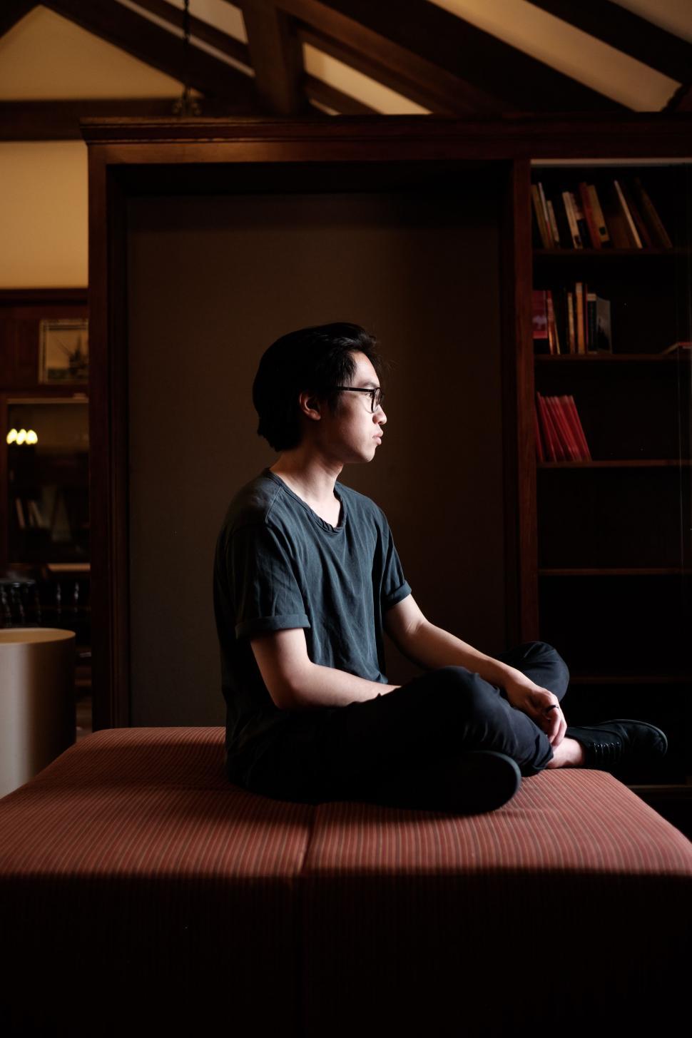 Free Image of Person Sitting on Bed in Room 