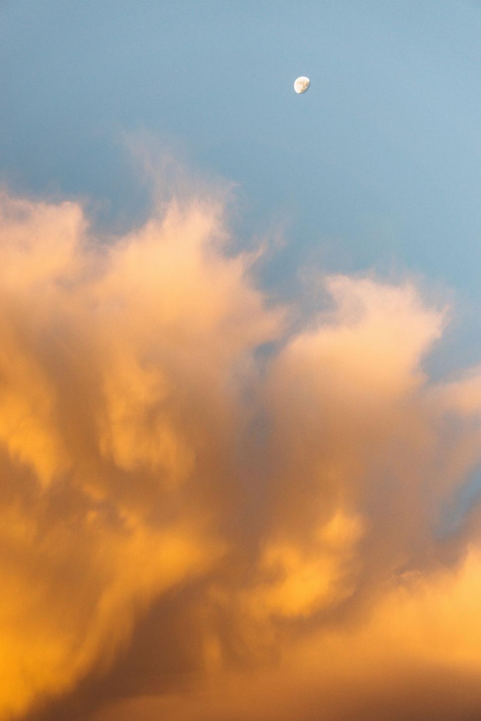 Free Image of Plane Flying Through Cloudy Sky With Moon in Distance 