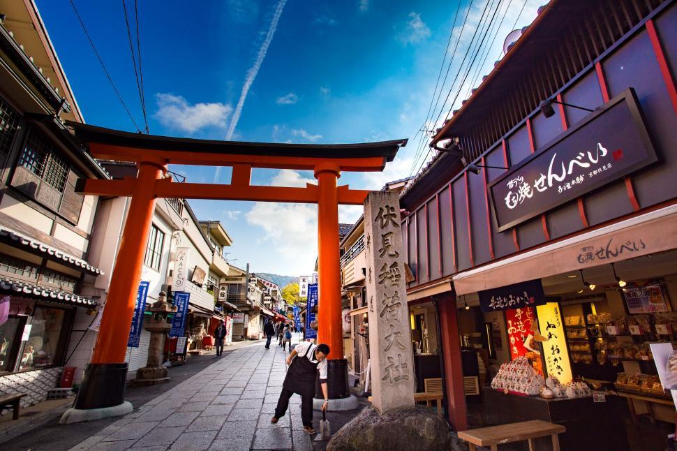 Free Image of Person Walking Down a Street Under a Blue Sky 