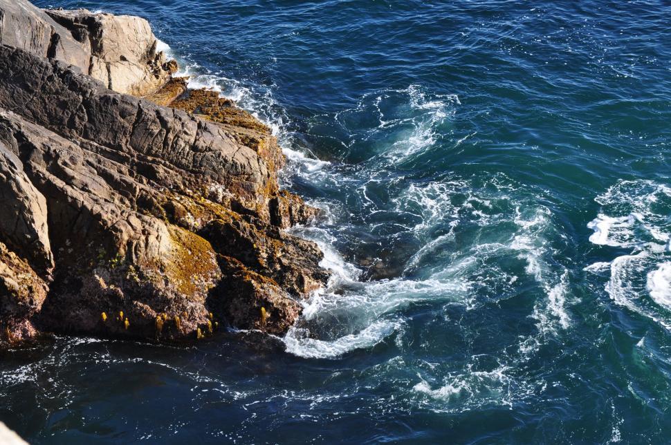 Free Image of Boat Sailing Near Rocky Shore 