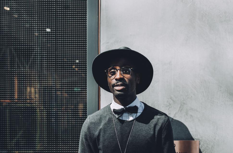 Free Image of Man Wearing Hat and Glasses Standing in Front of Window 