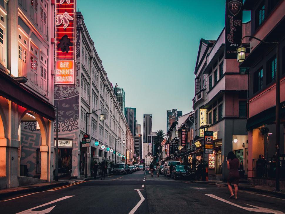 Free Image of Person Walking Down Street Next to Tall Buildings 