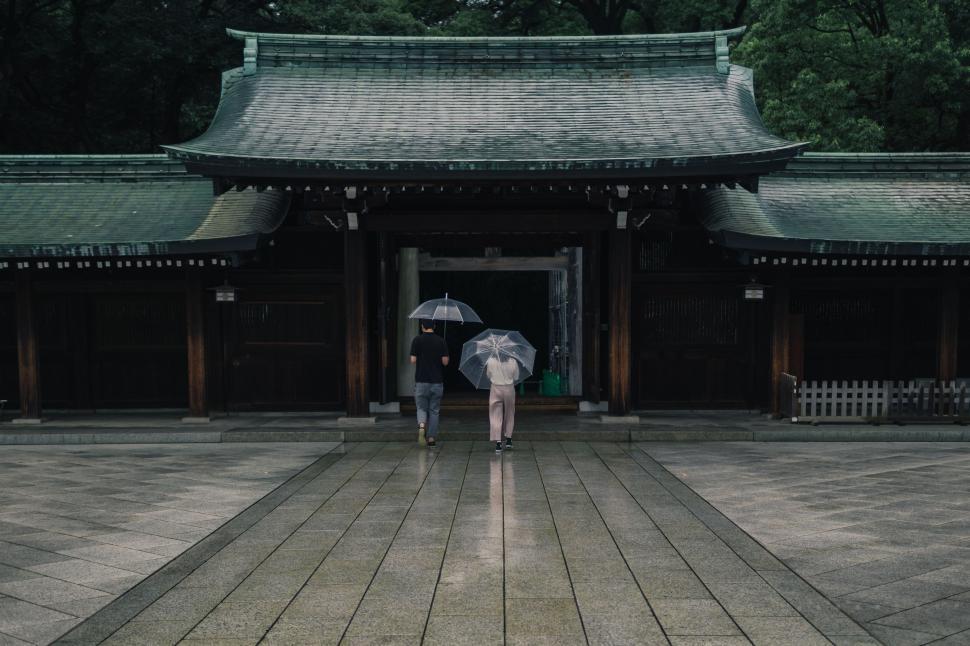 Free Image of Two People Holding Umbrellas in Front of a Building 