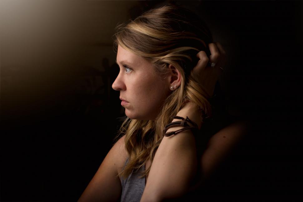 Free Image of Woman Sitting in Chair With Hand on Head 