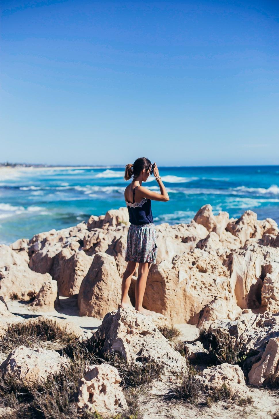 Free Image of Woman Standing on Rocky Beach by Ocean 