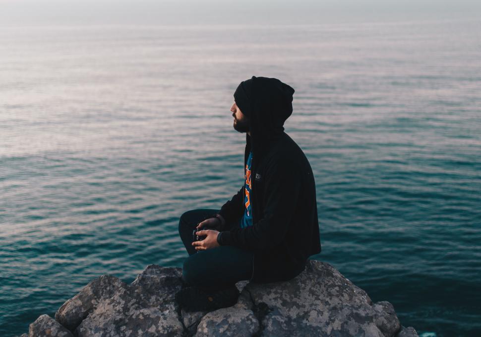 Free Image of Man Sitting on Rock by Ocean 