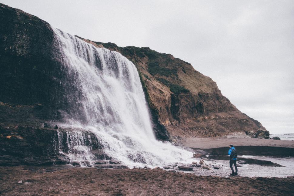 Free Image of Man Standing in Front of Waterfall 