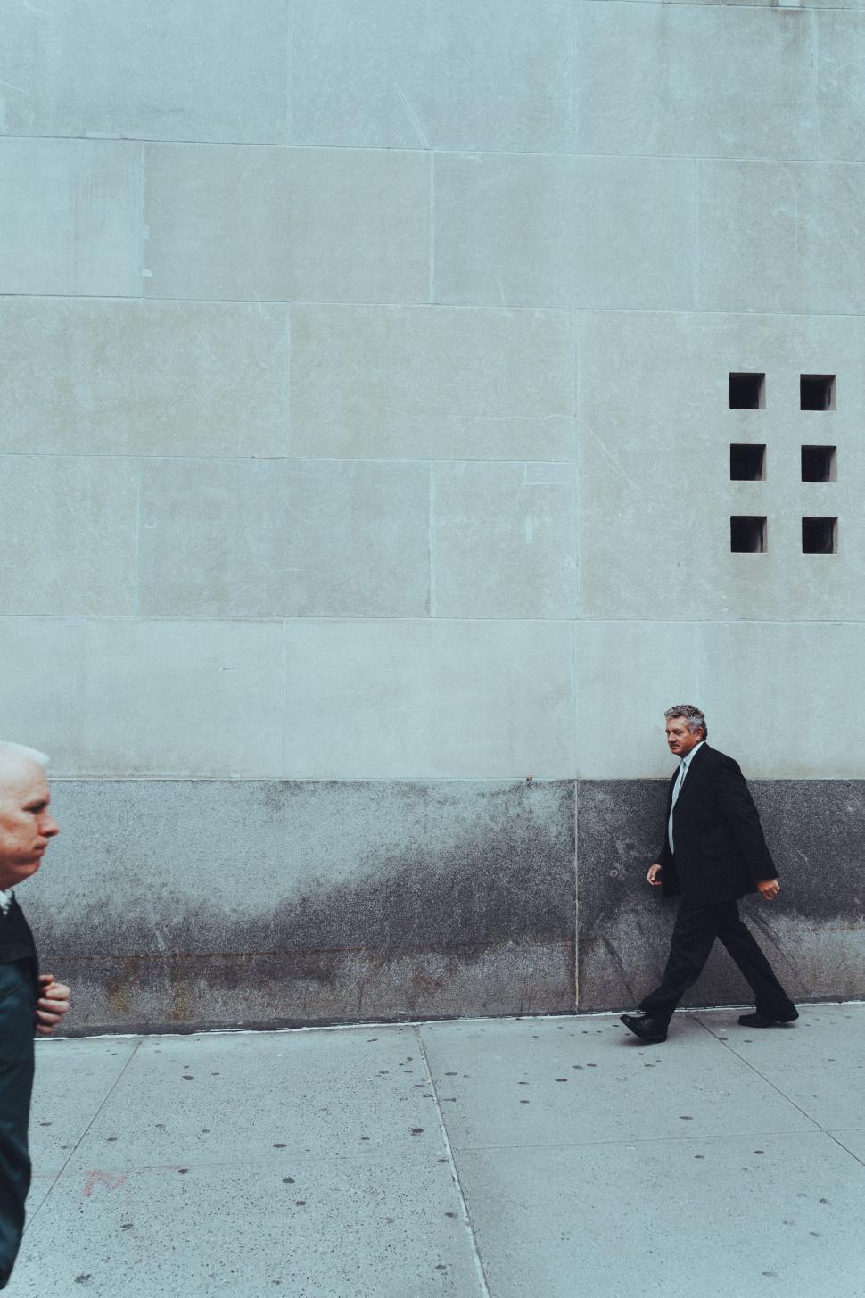 Free Image of A Man in a Suit and Tie Walking Down a Sidewalk 