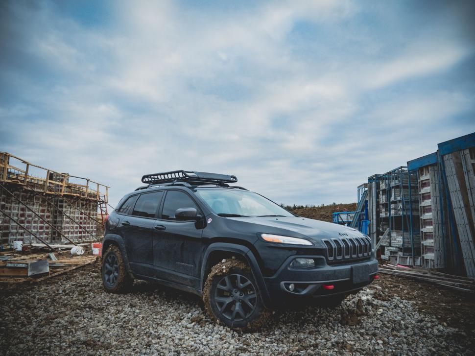 Free Image of Black Jeep Parked in Gravel Lot 