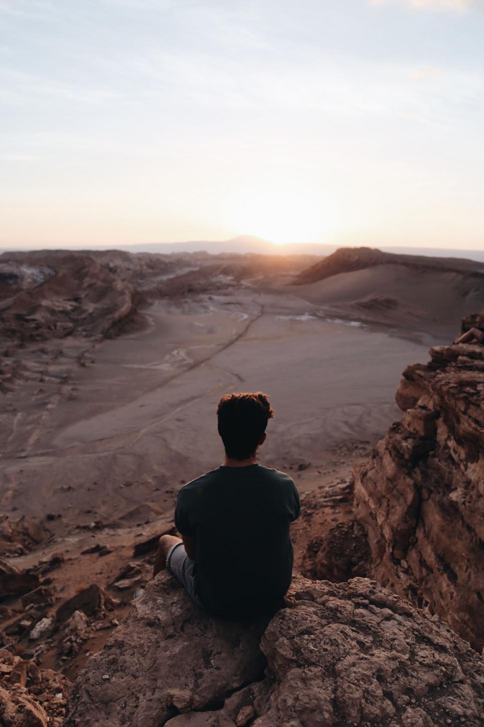 Free Image of Man Sitting on Top of Rocky Cliff 