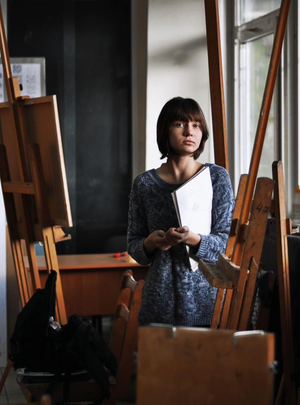 Free Image of Woman Standing in Front of Pile of Chairs 