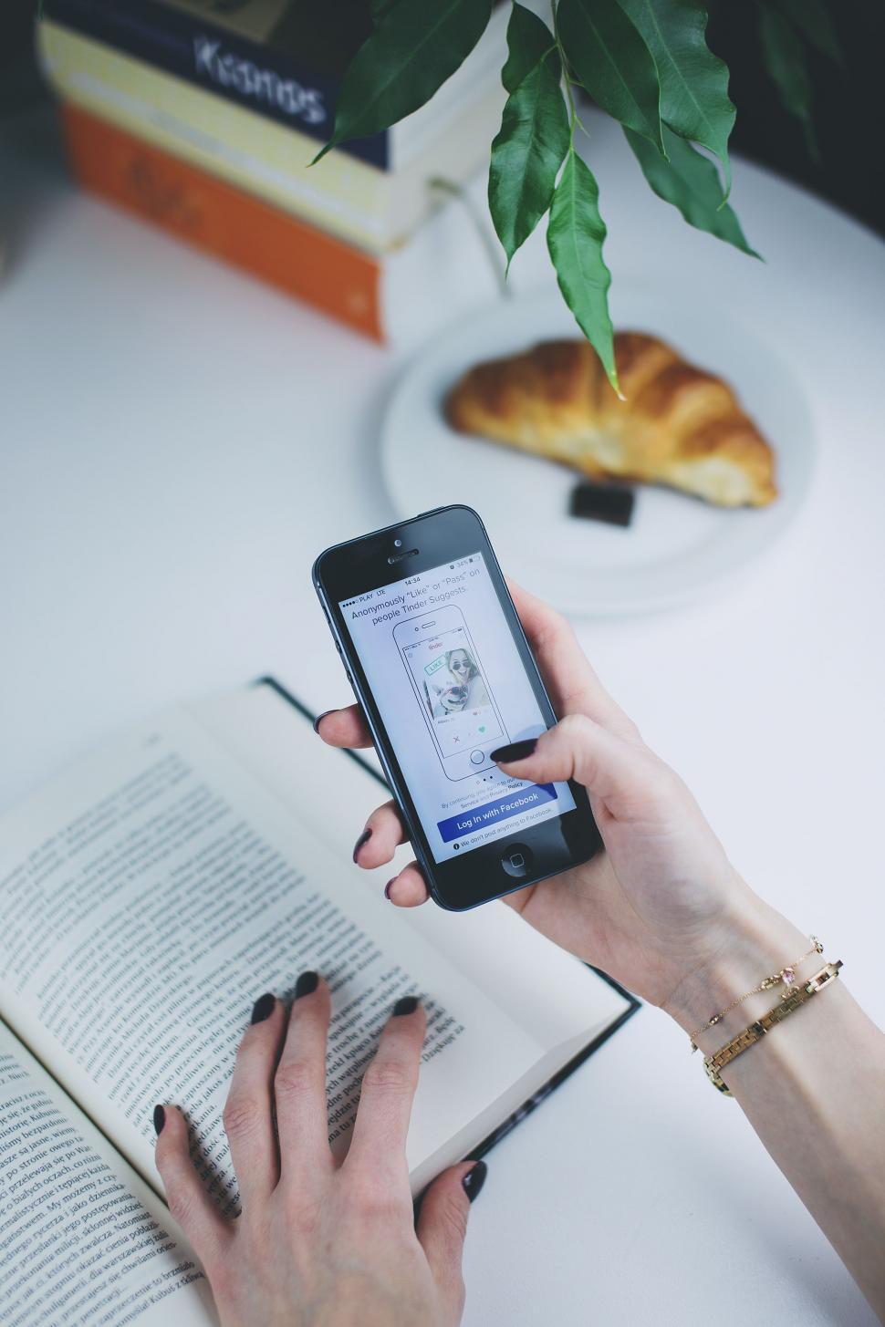 Free Image of Person Holding Cell Phone and Reading Book 