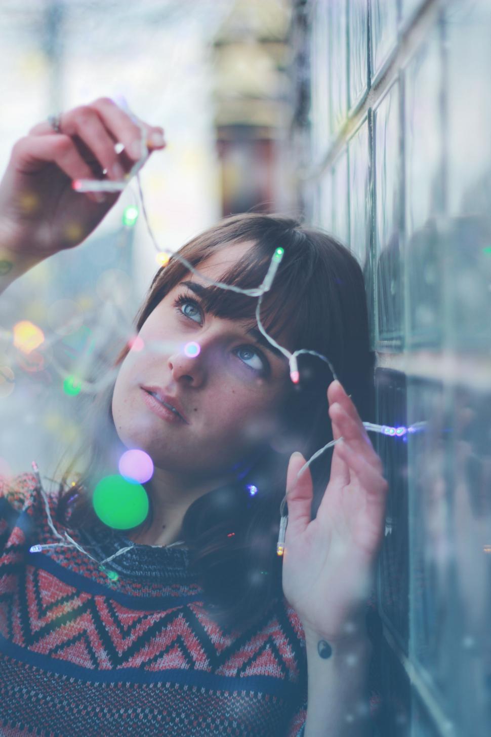 Free Image of Woman Leaning Against Wall With Hand on Ear 