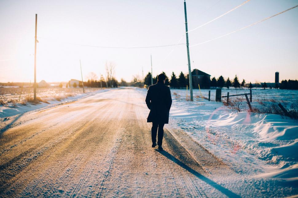 Free Image of Person Walking Down a Snow Covered Road 