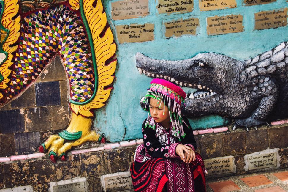 Free Image of Woman Sitting Next to Wall With Crocodile Painting 