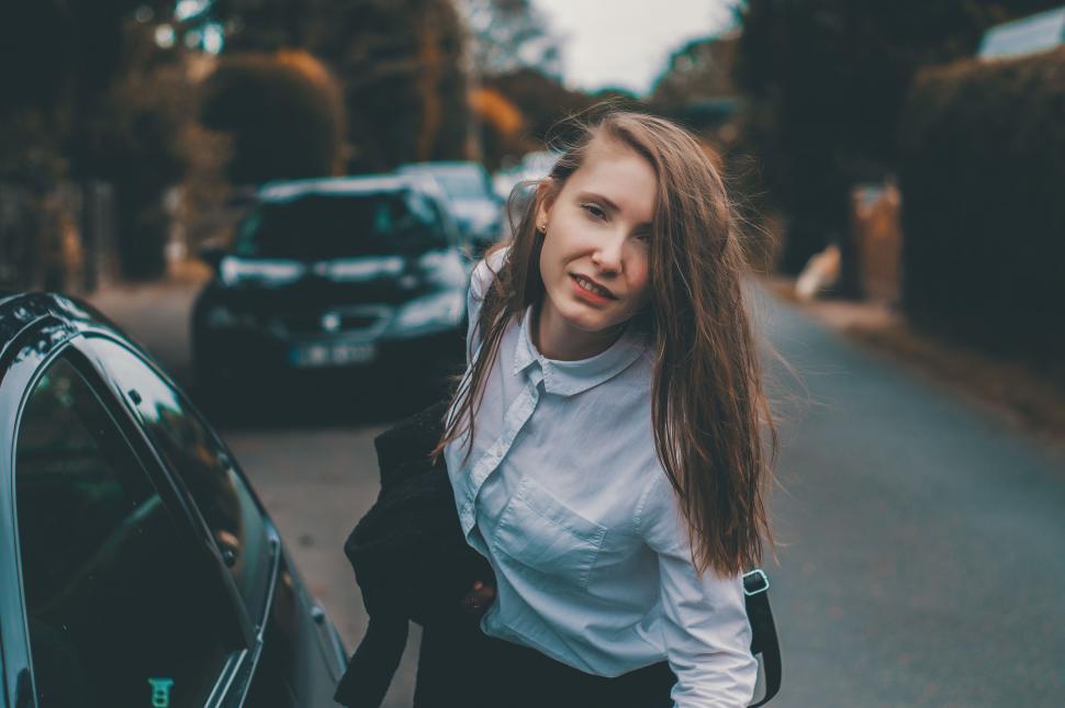 Free Image of Woman Walking Down Street Next to Car 