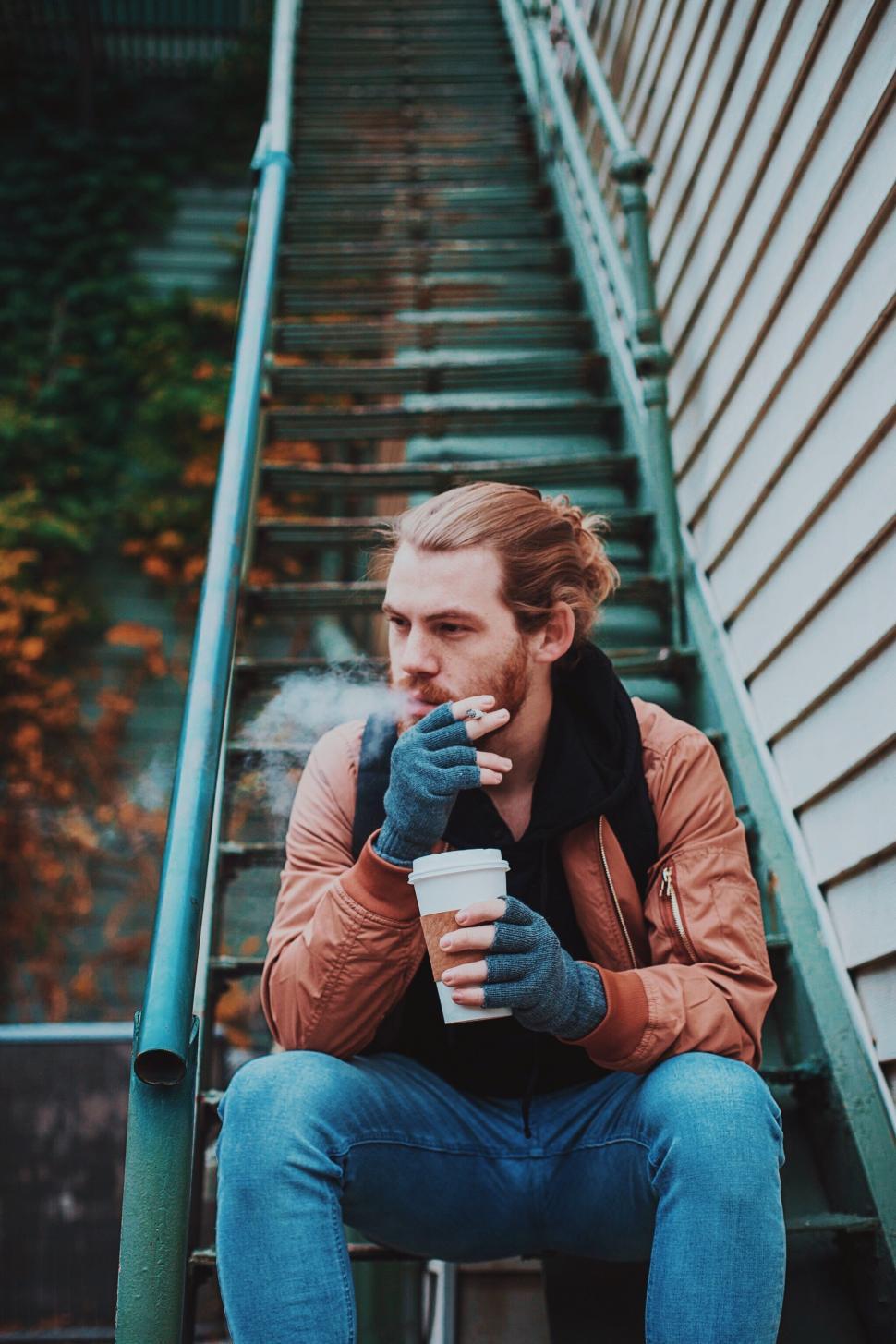 Free Image of Man Sitting on Stairs Smoking Cigarette 