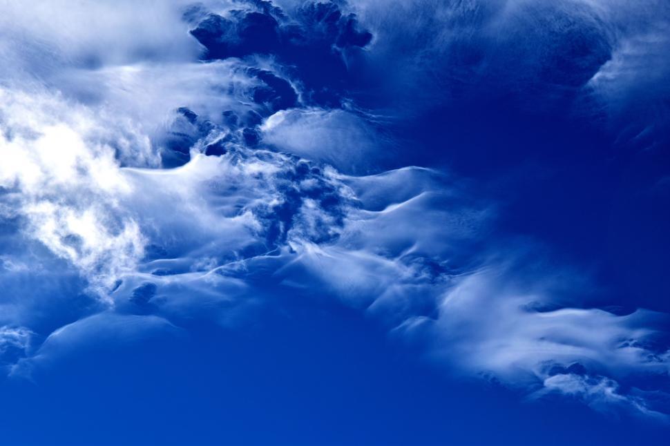 Free Image of A Plane Flying Through a Cloudy Blue Sky 