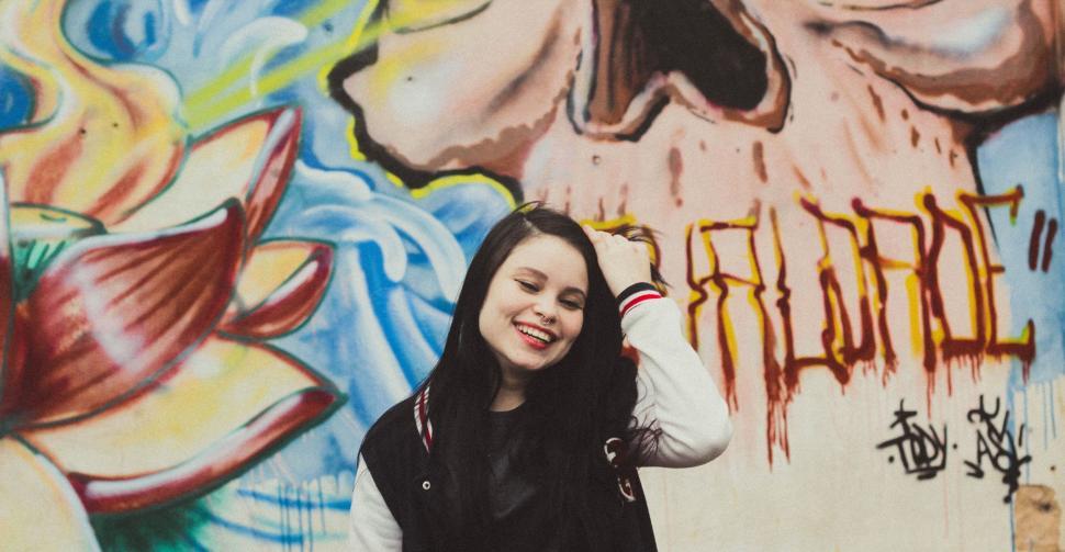 Free Image of Woman Standing in Front of Wall Covered in Graffiti 