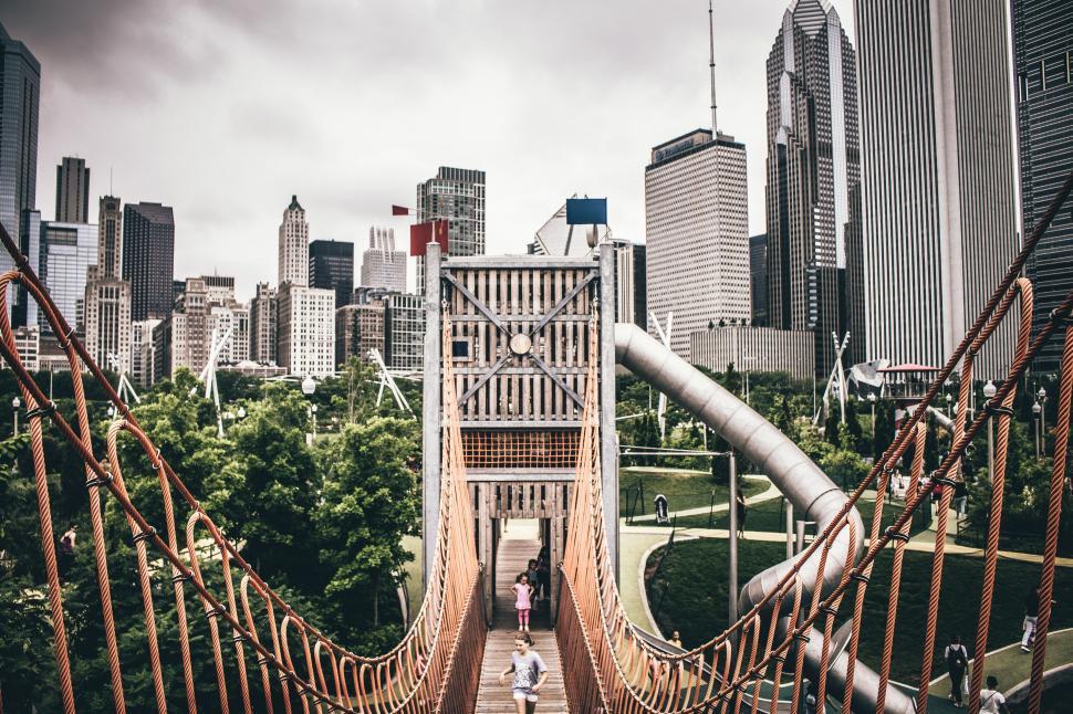 Free Image of Man Walking Across Bridge With City Background 