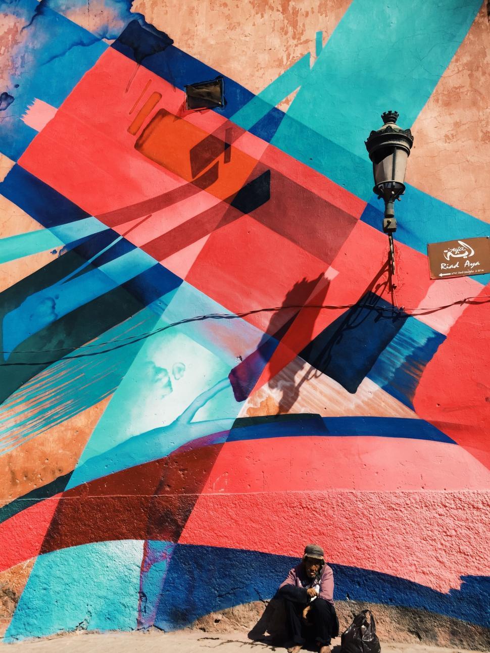 Free Image of Person Sitting on Ground in Front of Colorful Wall 