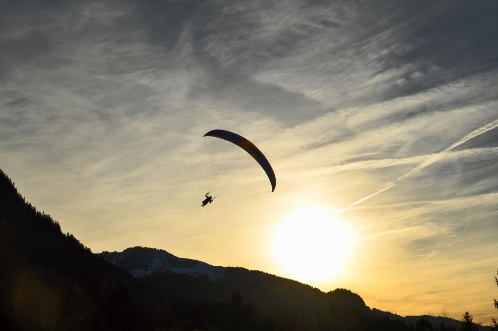 Free Image of Person Paragliding Over Mountain at Sunset 