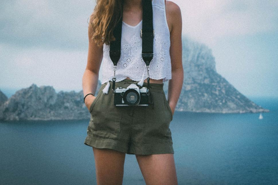Free Image of Woman With Camera Standing by Body of Water 