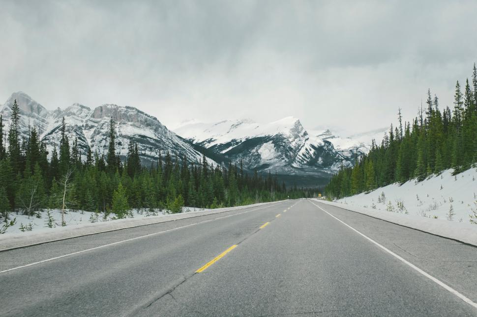 Free Image of Car Driving Down Road With Mountains in Background 