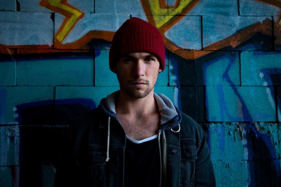 Free Image of Man Wearing Red Hat Standing in Front of Wall 