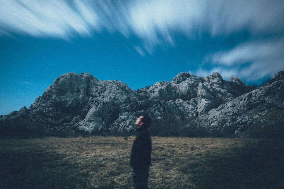 Free Image of Person Standing in Field With Mountains in Background 